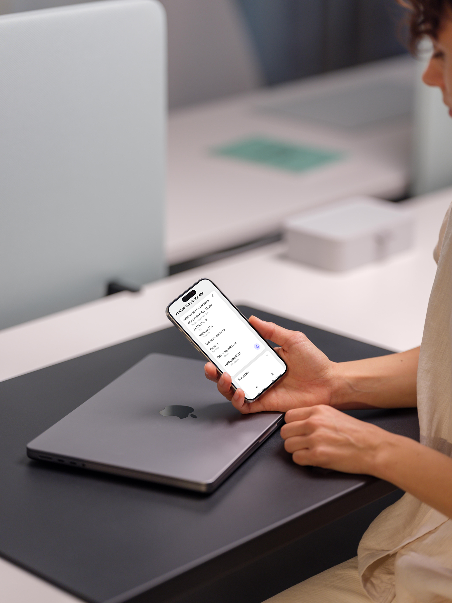 Diseñadora revisando una interfaz digital en laptop y teléfono, representando experiencias de usuario coherentes y multiplataforma
